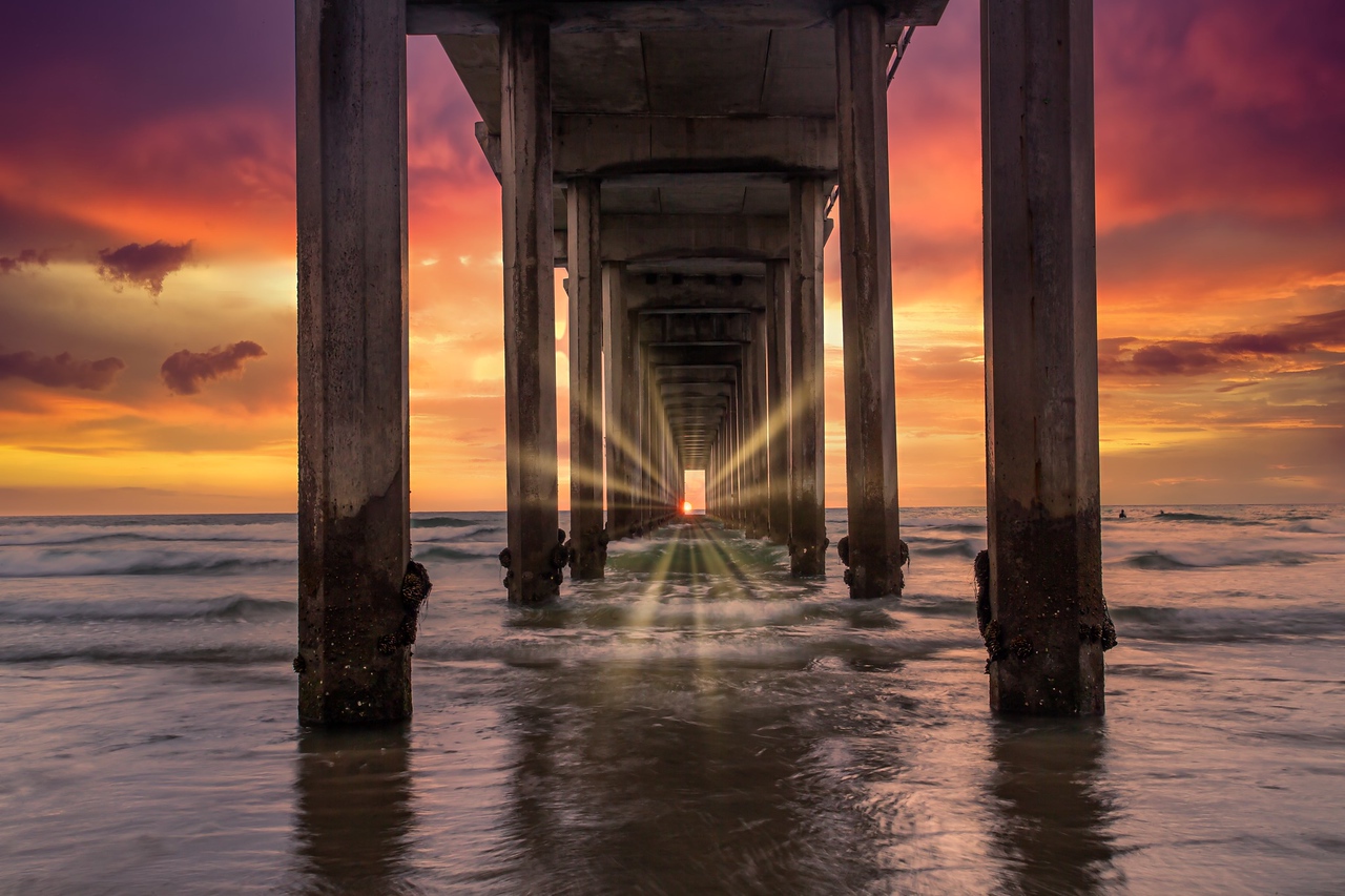 Sunset glowing beneath an ocean pier