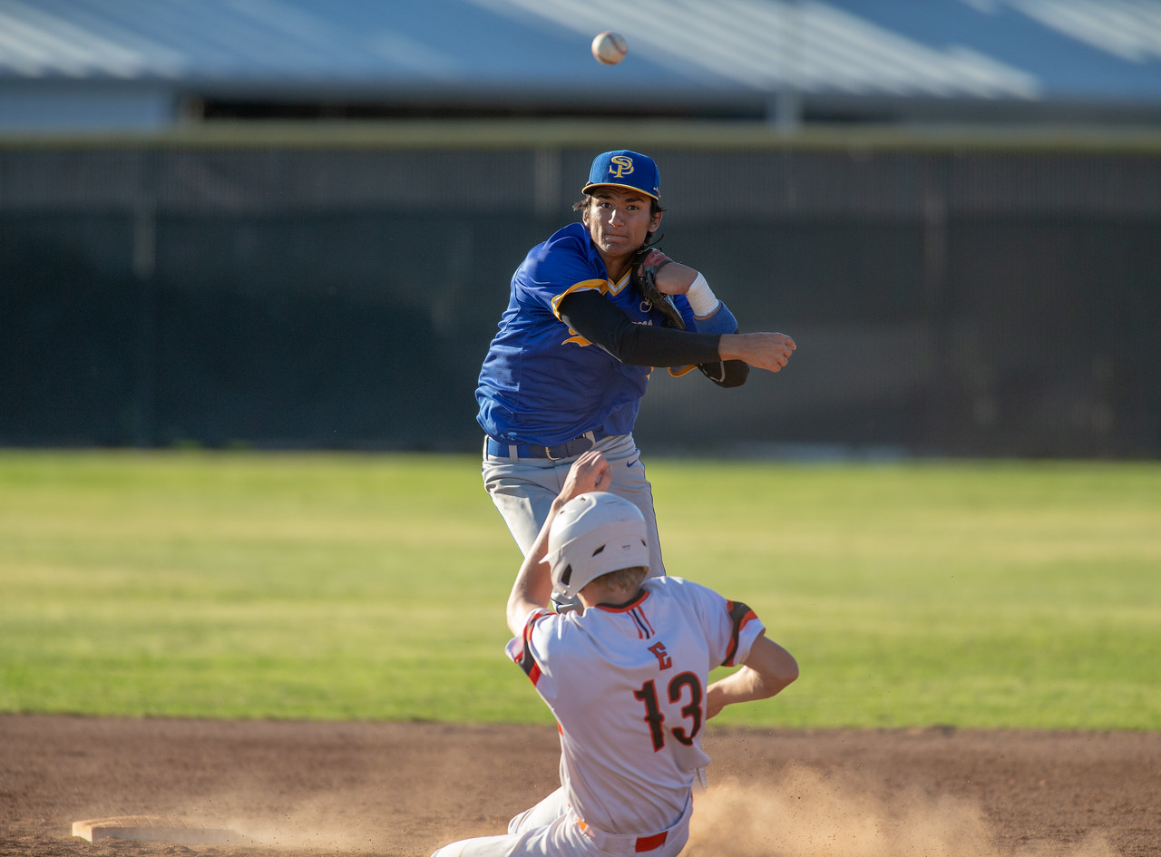 Runner slides into second as the shortstop leaps over him