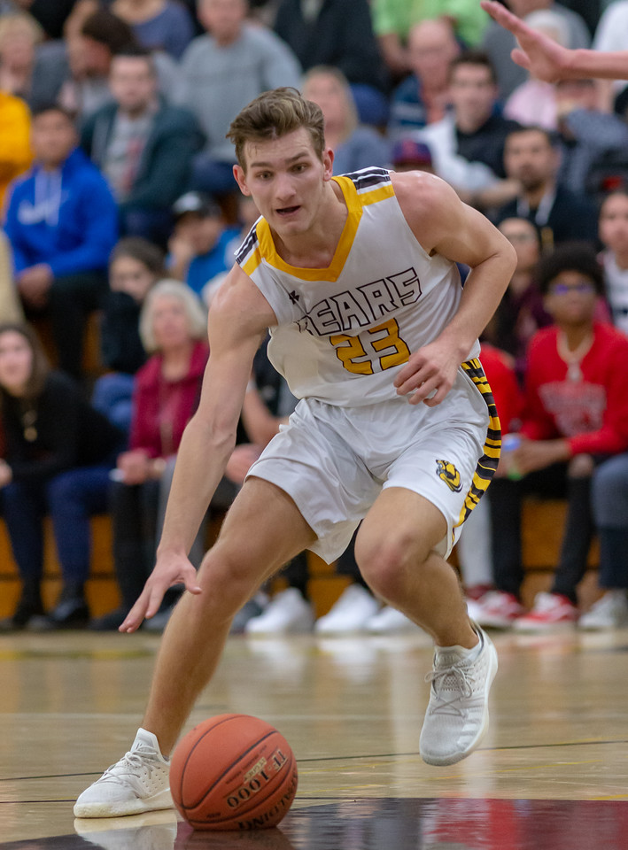 Basketball guard driving low past a packed crowd