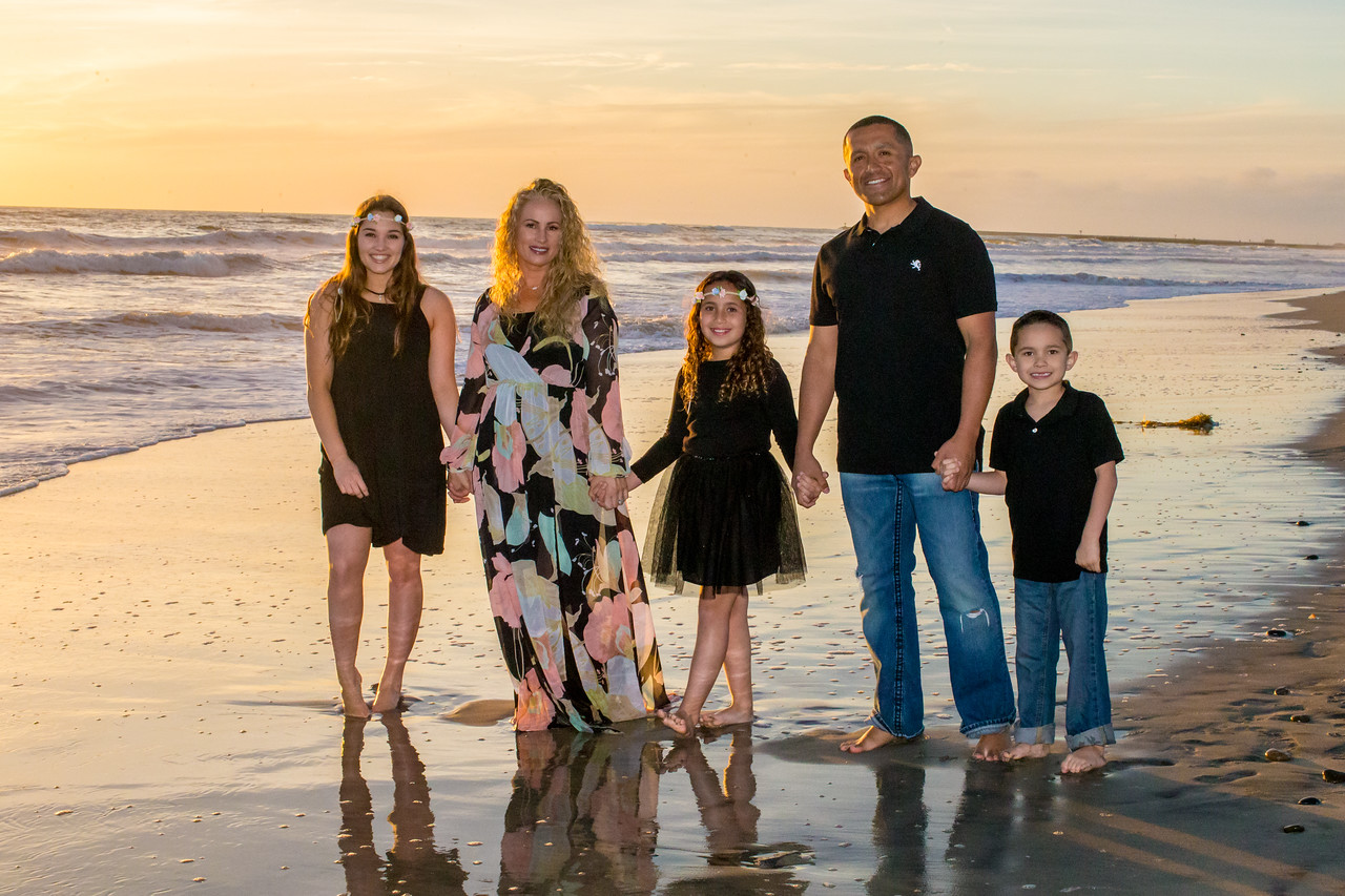 Family standing on the shoreline at sunset