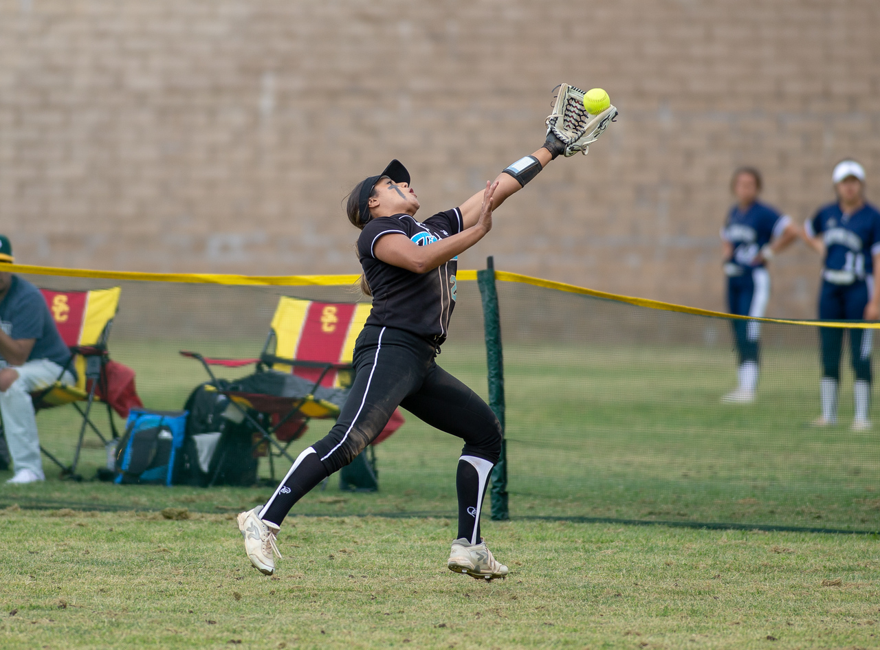 Outfielder stretching for a catch at the fence